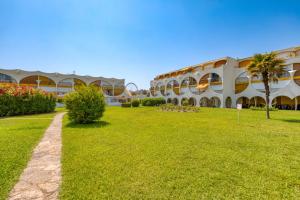 un bâtiment avec une cour herbeuse devant lui dans l'établissement Appartement à 70m de la plage, à La Grande Motte