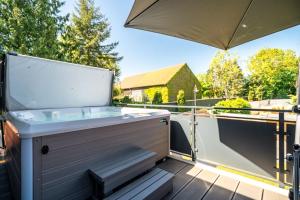 a hot tub on a deck with an umbrella at Ferienwohnung ScheunenBlick in Göhren-Lebbin