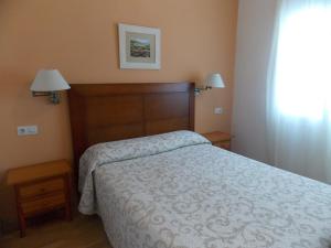 a bedroom with a bed and two lamps and a window at Pensión La Palma in El Puerto de Santa María