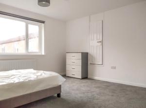 a bedroom with a bed and a dresser and a window at City Vacations Corby 4 separate room house in Corby