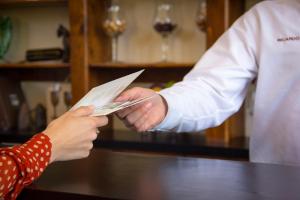 una persona que entrega a otra persona un pedazo de papel en Hacienda Guadalupe Hotel en Valle de Guadalupe