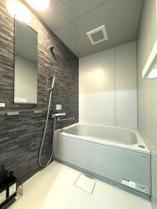 ein Badezimmer mit Badewanne und Spiegel in der Unterkunft K square 400 in Nagoya