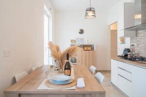 a kitchen with a wooden table with plates and wine bottles at Casa Alejandra a Pachino centro in Pachino +18 photos