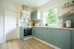 a kitchen with blue cabinets and a window at Ferienhaus Strandnest in Ahlbeck