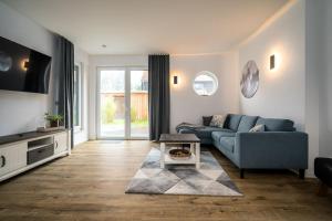 a living room with a blue couch and a tv at Ferienwohnung FleesenNest in Göhren-Lebbin