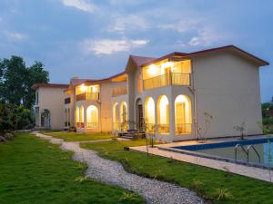 a large house with a pool in front of it at Evaan Litchi Orchards and Resorts, Corbett in Rāmnagar