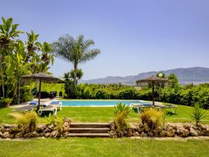 a pool with tables and umbrellas in a yard at Cubo's Casa Rural El Oasis De Don Pedro in Villafranco de Guadalhorce