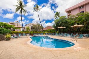 a swimming pool at a resort with chairs and palm trees at Oceanview Kahana Villa - Walk to Beach & Dining in Kahana