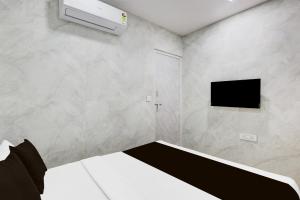 a bedroom with a bed and a tv on a wall at Hotel O Lotus in Surat +21 photos