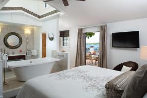 uma casa de banho branca com uma banheira e uma cama em Black Dolphin Inn em New Smyrna Beach