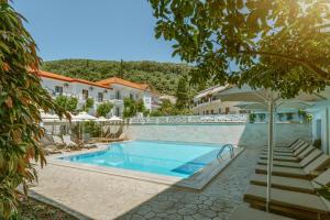 a pool at a hotel with chairs and an umbrella at Hotel Rezi in Parga