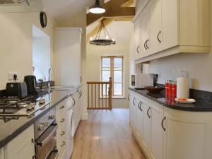 a large kitchen with white cabinets and black counter tops at The Granary in Tiverton