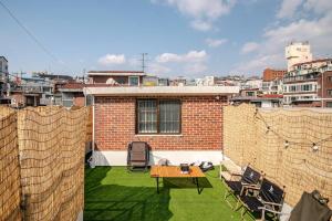 a patio with a table and chairs on a roof at Pachira House in Seoul