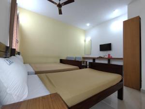 坦贾武尔Naadi Hotel New Busstand Thanjavur的一间有两张床和一台电视的小房间