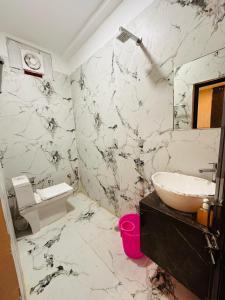 a white marble bathroom with a sink and a toilet at Hotel Airport Highway Suitable for Family and Business Travellers in Lucknow