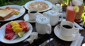 a table with plates of food and cups of coffee at Rumah Tenun in Karangasem +37 photos