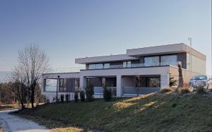 a house on a hill with a car parked in front at Apartmány Panoráma Bojnice in Bojnice