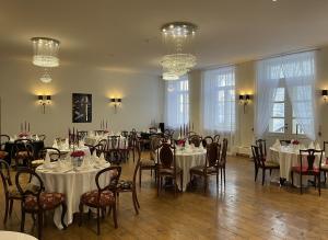 a dining room with tables and chairs and chandeliers at Hof Podis Pootsi veinimõis in Pootsi