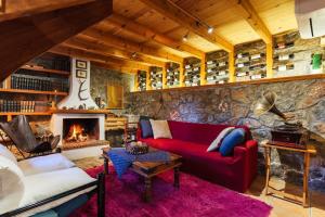 a living room with a red couch and a stone wall at Pine Forest Chalet 1400m, Cinema & Fireplace in Artemisía