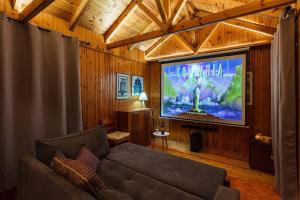 a living room with a couch and a big screen tv at Stone Forest Escape - Cozy Cinema & Starry Sky in Artemisía