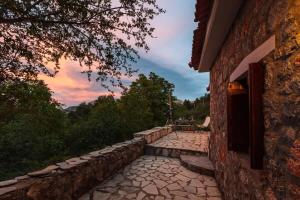 a stone walkway next to a building with a sunset at Stone Forest Escape - Cozy Cinema & Starry Sky in Artemisía