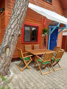 a wooden table and chairs next to a tree at Sosnowy domek in Pobierowo