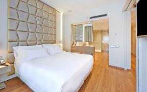 a bedroom with a large white bed and a bathroom at NH Collection Barcelona Podium in Barcelona