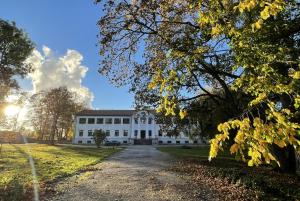a white building on a field with trees at Hof Podis Pootsi veinimõis in Pootsi