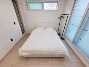 een wit bed in een witte kamer met een raam bij Luxury Terrace House in Seoul