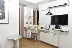 a white bathroom with a television and a sink at Levent Lavandula Hotel in Istanbul