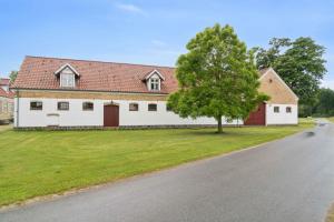 una casa con un árbol al costado de una carretera en Margretehøj Manor In Scenic Surroundings, en Rimsø