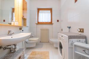 a white bathroom with a sink and a washing machine at Ciase Strim in Falcade