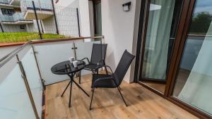 a balcony with two chairs and a table at Perła Mierzei, Sun & Snow in Sztutowo