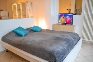 1 dormitorio con 1 cama con almohadas azules y TV en Residenz Lagobello, en Germignaga