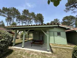 a green shed with a picnic table under a roof at Les ajoncs in Brocas +8 photos