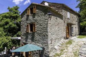 an old stone building with a blue umbrella in front at Appartamento Ponte Nuovo Premilcuore in Premilcuore