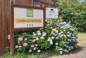 znak przed krzakiem kwiatów w obiekcie Camping Onlycamp Les Deux Rives w mieście Lannion