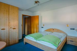 a bedroom with a large bed with green and blue pillows at Reiterlandhof in Neukirchen +8 photos
