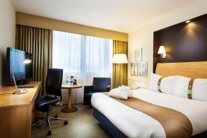 a hotel room with a bed and a desk and a television at Holiday Inn - Glasgow Airport by IHG in Paisley