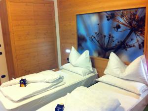 フォルガリーアにあるRelais Fior di Boscoの白い枕が置かれたホテルの部屋にはベッドが2つある +52枚の写真