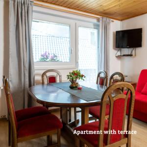 a dining room table with chairs and a red couch at Apartmaji Taler in Bohinj