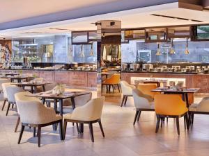 a restaurant with tables and chairs and a kitchen at Grand Mercure Bali Seminyak in Seminyak