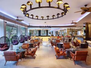 a restaurant with tables and chairs and a chandelier at Grand Mercure Bali Seminyak in Seminyak
