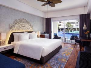 a bedroom with a large white bed and a balcony at Grand Mercure Bali Seminyak in Seminyak