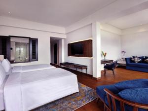 a bedroom with a white bed and a blue couch at Grand Mercure Bali Seminyak in Seminyak