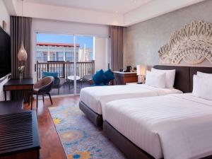 a hotel room with two beds and a balcony at Grand Mercure Bali Seminyak in Seminyak