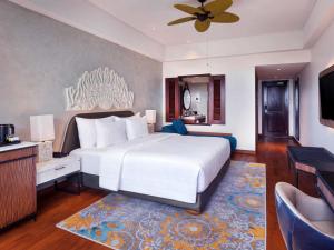 a bedroom with a large white bed and a flat screen tv at Grand Mercure Bali Seminyak in Seminyak