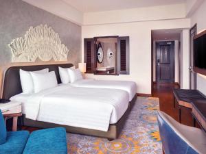 a bedroom with a large bed and a living room at Grand Mercure Bali Seminyak in Seminyak