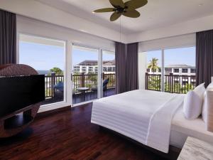 a bedroom with a large bed and a balcony at Grand Mercure Bali Seminyak in Seminyak