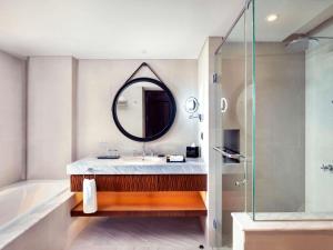a bathroom with a sink and a mirror and a tub at Grand Mercure Bali Seminyak in Seminyak